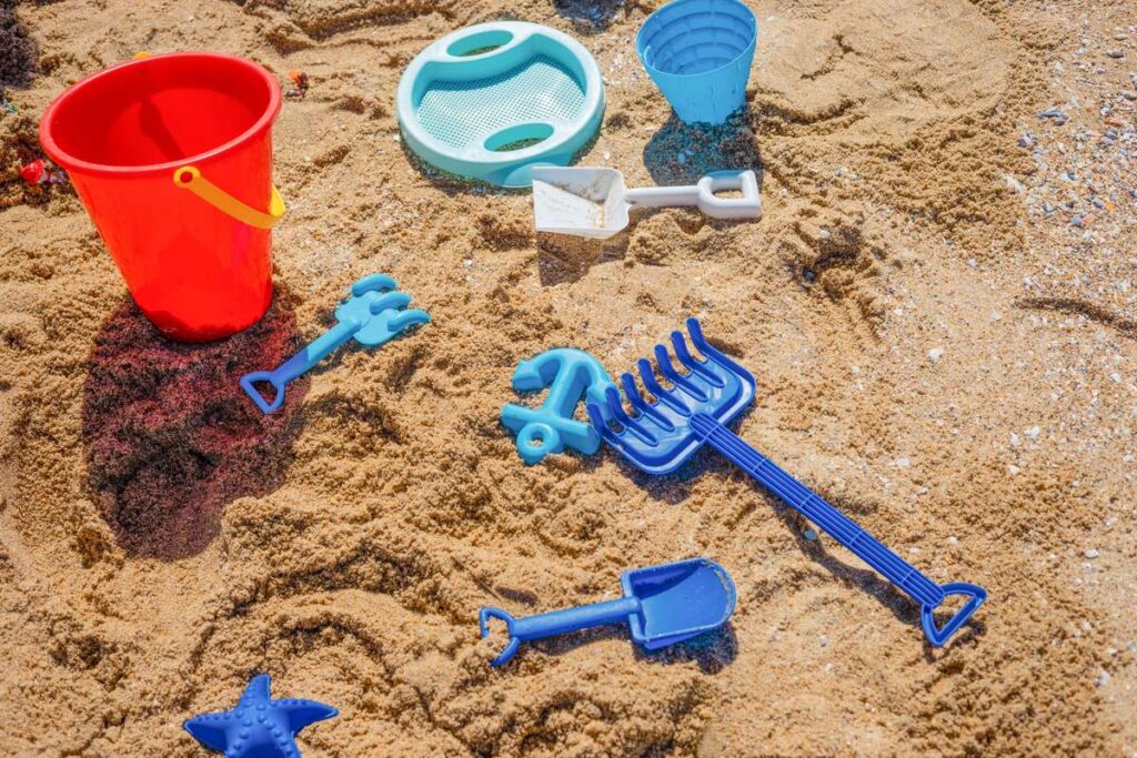 Eimer, Schaufeln und Förmchen aus Plastik im Sand
